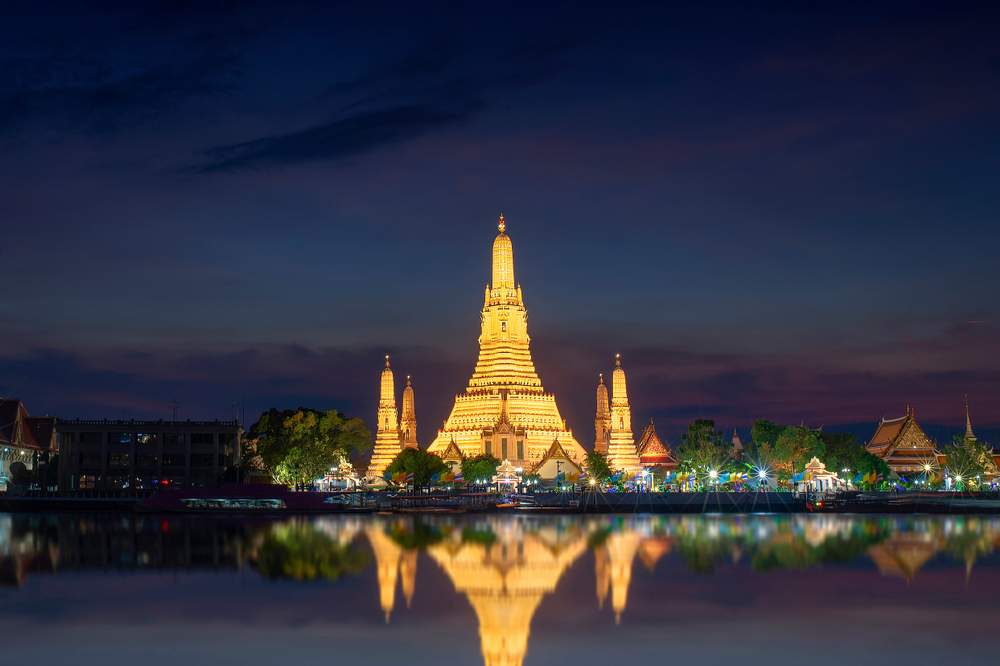 Wat Arun temple illuminated by lights against night sky