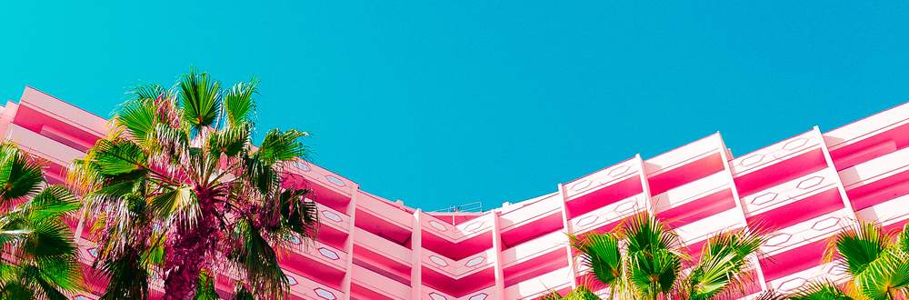 Palm trees in front of a pink hotel