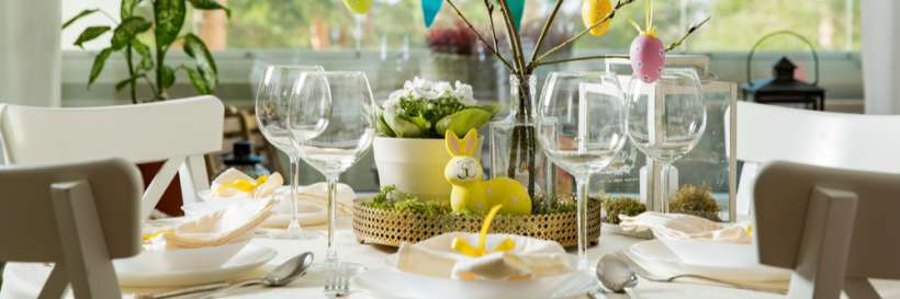 Easter dinner table set up with wine glasses and egg and bunny ornaments