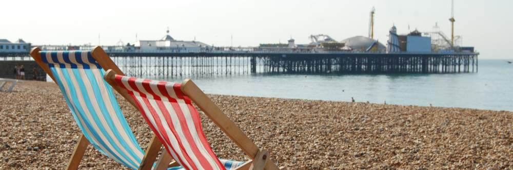 deckchairs on the beach with pier in background