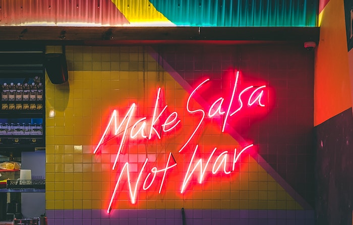 Neon sign saying 'Make Salsa Not War'